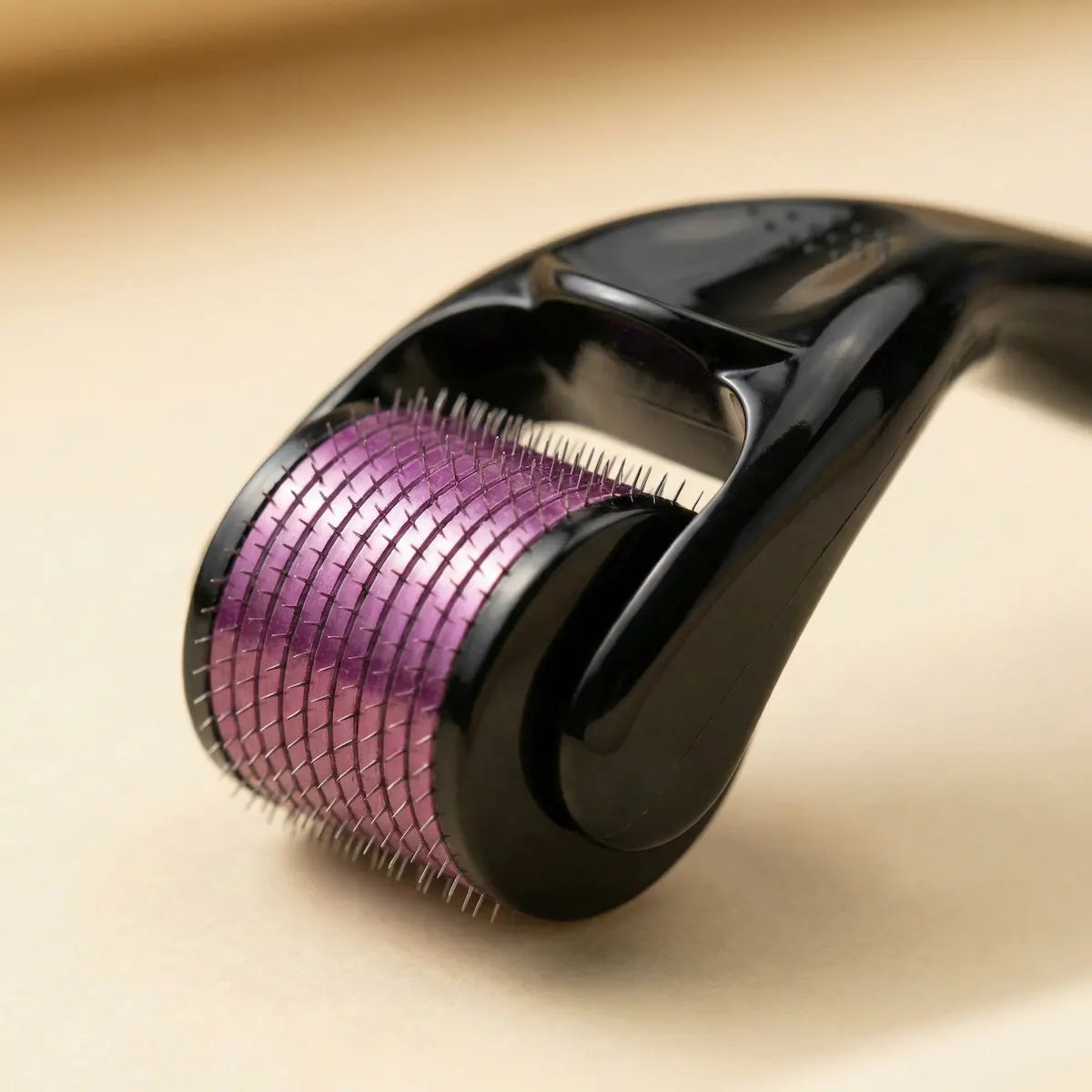 Derma roller with purple metallic head on a beige background